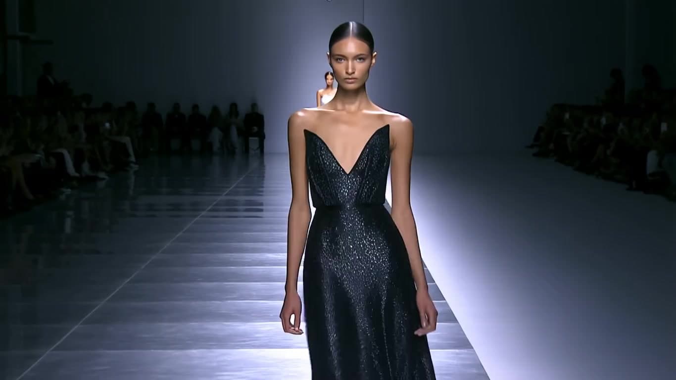 the female model walks down a fashion runway with strong posture and focused eyes