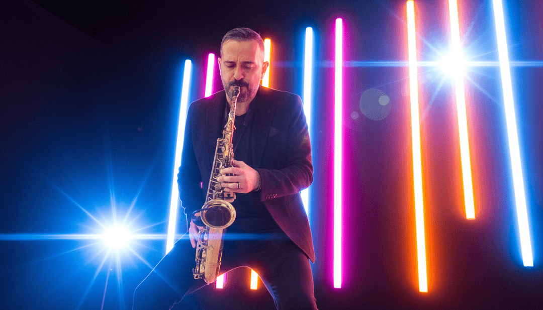 एक उत्साहित संगीतकार अपनी नव-जनित एआई म्यूजिक वीडियो को बड़ी स्क्रीन पर देख रहा है, सशक्त और रचनात्मक दिख रहा है, जिसमें freebeat.ai का लोगो दिखाई दे रहा है।